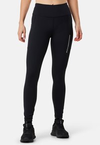 Black athletic leggings with a high waist, featuring side pockets and reflective details along the seams. Made from smooth, stretchy material.