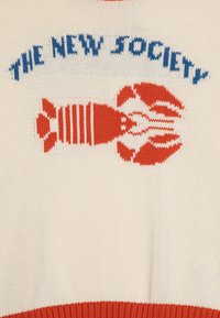 Pull en tricot crème avec un graphisme de homard rouge et le texte bleu "THE NEW SOCIETY." Ourlet rouge côtelé et texture lisse sur l'ensemble.