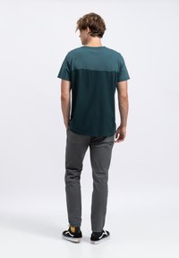 Turbote kleurig T-shirt met korte mouwen met een gradient effect, gecombineerd met grijze tapered broeken en zwarte sneakers. Heeft een ronde halslijn en een ontspannen pasvorm.