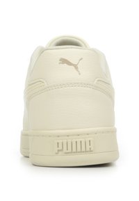 Vista posteriore di una sneaker Puma color off-white con suola testurizzata, logo Puma impresso sul tallone e logo Puma cat nella parte superiore posteriore.