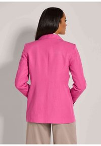 Aangepaste roze blazer met een notch revers, getailleerd silhouet en een soepele stof. Lange mouwen en een naden detail aan de achterkant zijn zichtbaar.