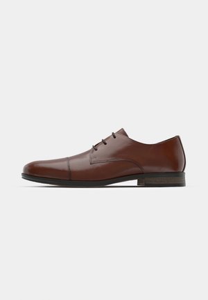 Brązowe skórzane buty eleganckie z gładkim wykończeniem, zaokrąglonym noskiem i trzema oczkami do sznurowania. Posiadają niski obcas i teksturowaną podeszwę.
