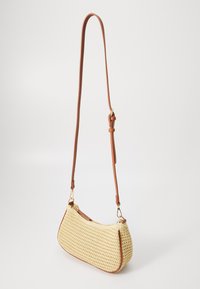 Kožený ramenní popruh v hnědé barvě je připevněn k tkané kabelce krémové barvy se zaobleným, strukturovaným tvarem a texturovaným povrchem. Zlato-tonované kovové doplňky.