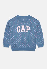Modra sweatshirt z okroglim izrezom, ki ima ponavljajoč se cvetlični vzorec in izstopajoč bel logotip "GAP" v svetlo roza barvi.