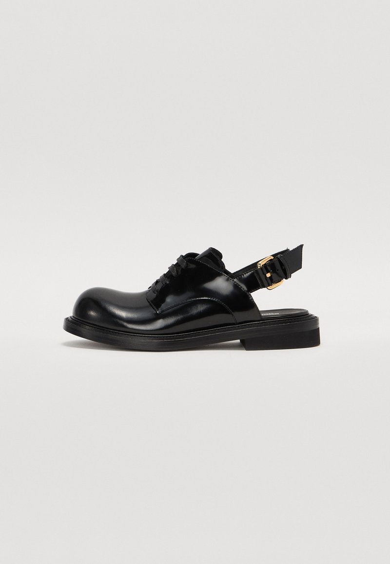 Black leather slingback shoes featuring a rounded toe, lace-up front, and a side buckle detail. Smooth texture with a flat sole.
