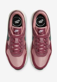Baskets Nike Air avec un design bordeaux et rose, matériaux textile et cuir, bout rond, et semelle intérieure noire contrastante avec logo.