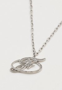 Κολιέ αλυσίδα από ασημί με κρεμαστό γράμμα σε γραφή ρεύματος, διακοσμημένο με μικρές διαφανείς πέτρες. Το μενταγιόν διαθέτει λείο και υφή φινίρισμα.