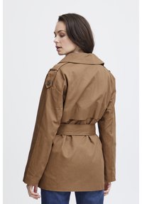 Brauner Trenchcoat mit taillierten Gürtel, großem Kragen, Schulterklappen und lockerer Passform. Hergestellt aus einem glatten, strukturierten Stoff.