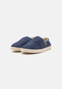 Blue quilted slip-on shoes with a soft beige lining and lightweight rubber sole, featuring a low profile and a textured upper.