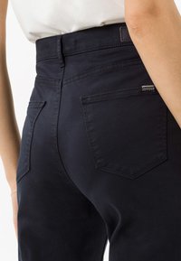 Pantaloni alta vita blu navy realizzati in morbido cotone, dotati di due tasche posteriori e dettagli di cucitura minimali e poco visibili.