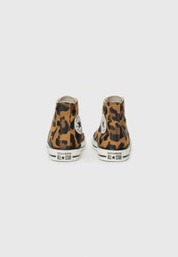 Par visoko visokih Converse All Star tenisica u leopard uzorku prikazanih sa stražnje strane na bijeloj pozadini.