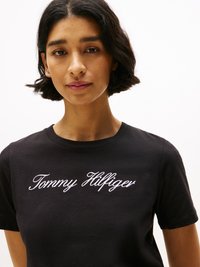 T-shirt en coton noir avec le logo "Tommy Hilfiger" brodé en blanc sur le devant. Col rond et manches courtes, coupe décontractée.