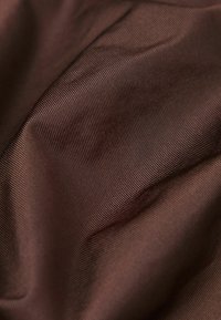 Hnědá saténová látka s hladkou, lesklou texturou a jemným žebrovaným vzorem, vykazující jemné nabrání a záhyby.