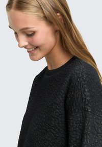 Schwarzer strukturierter Pullover mit gewobenem Muster und subtiler Schattierung, klassischem Rundhalsausschnitt und lockerer Passform.