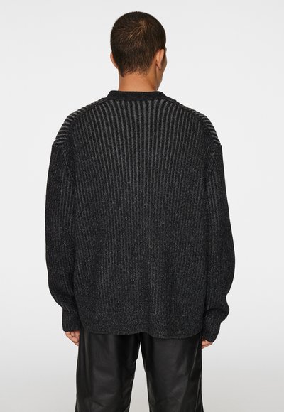 Overdimensioneret sort sweater med ribbet tekstur, brede ærmer og en subtil glans. Har en struktureret yoke og en afslappet pasform for komfort.