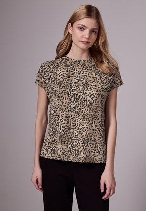 Top corto a maniche corte con stampa leopardata in beige e macchie nere. Collo rotondo e vestibilità comoda, realizzato in tessuto morbido, abbinato a pantaloni scuri.
