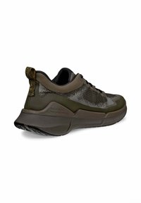 Brauner Sportschuh mit strukturiertem Obermaterial und einer dicken, gepolsterten Sohle. Verfügt über eine gemusterte Fersenlasche und dunkle Schnürsenkel.