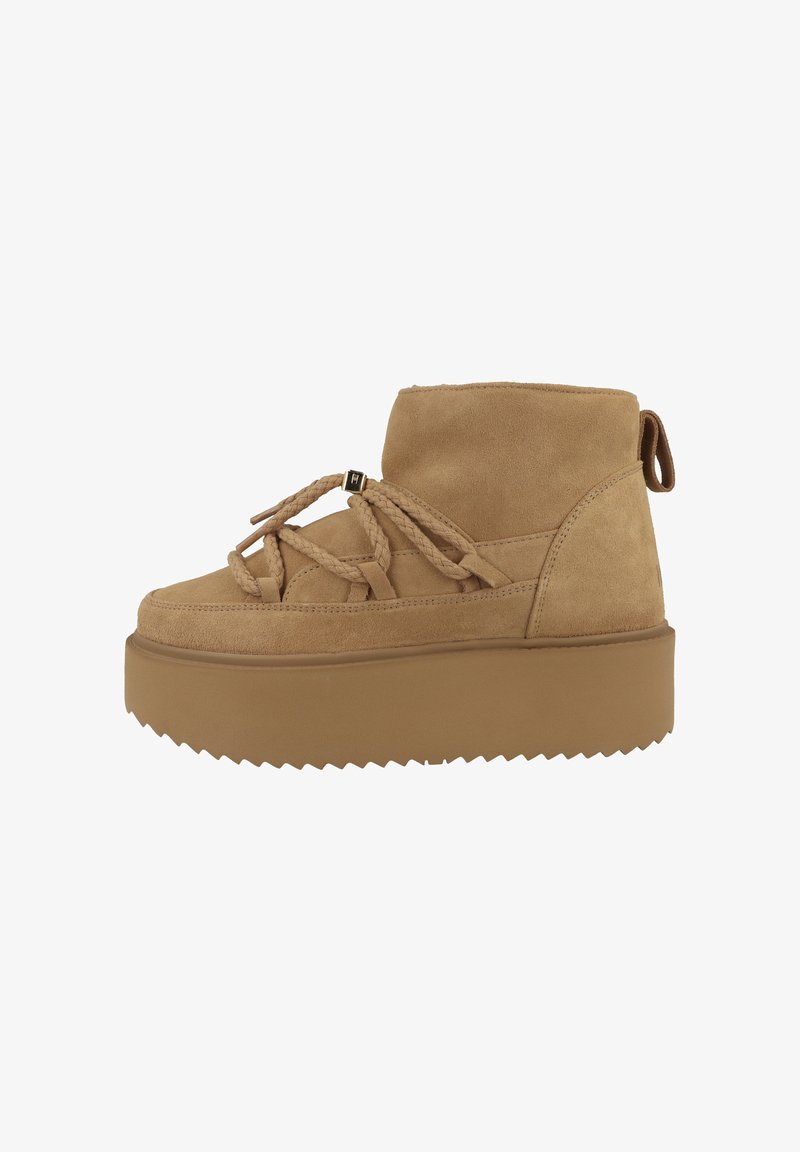 Stivale alla caviglia in suede color sabbia con suola spessa e strutturata, dotato di lacci intrecciati e un pratico pull tab sul retro per facilitarne l'indossamento.