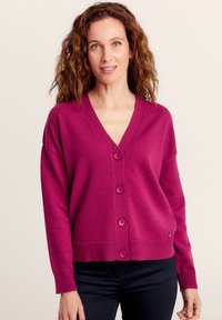 Cardigan lavorato a maglia fucsia con scollatura a V, maniche lunghe e cinque bottoni sul davanti. Orlo e polsini a coste, texture morbida.