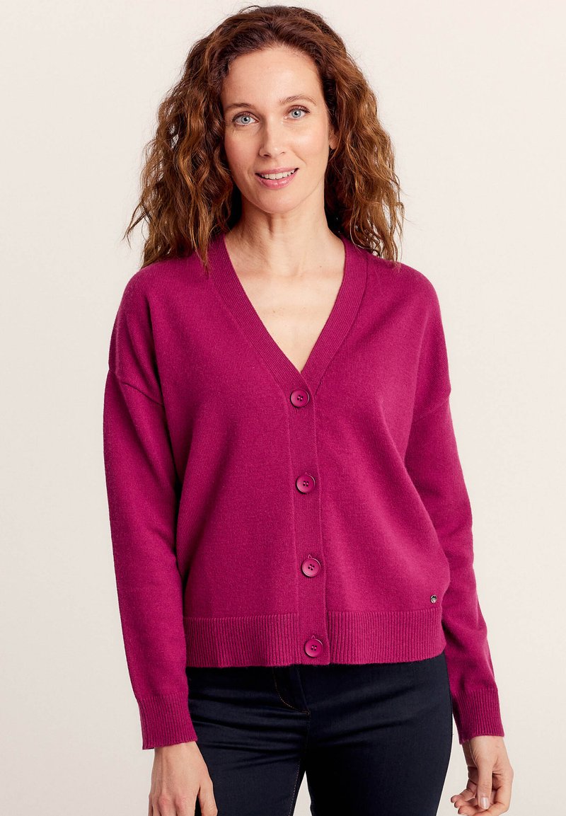 Cardigan lavorato a maglia fucsia con scollatura a V, maniche lunghe e cinque bottoni sul davanti. Orlo e polsini a coste, texture morbida.