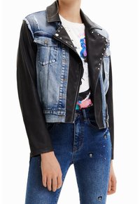 Jeansjacka i denim och läder som kombinerar ljusblå denim med svarta läderslevar, med silvernitar på kragen och en kortad design.