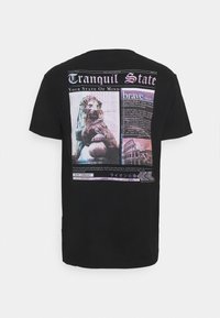 Svart t-shirt med ett grafiskt tryck av ett lejon, textinslag och arkitektoniska bilder i färgerna kräm, rosa och lila.