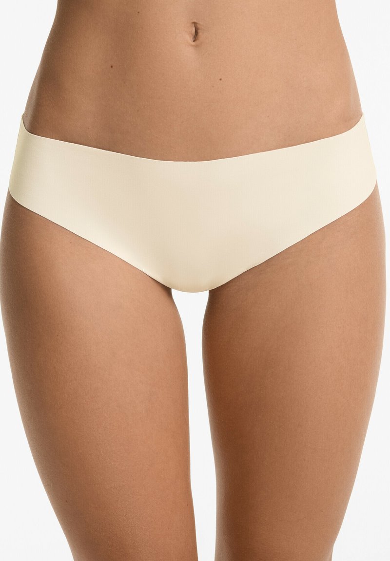 Béžové bezšvové bikini nohavičky s hladkým povrchom a širokým pásom, navrhnuté pre pohodlné nosenie a minimálnu viditeľnosť pod oblečením.