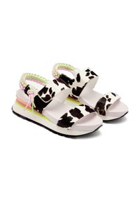 Sandalias de plataforma con una base blanca y estampado de vaca negro. Correas ajustables con detalles trenzados en rosa y verde. Suela gruesa.
