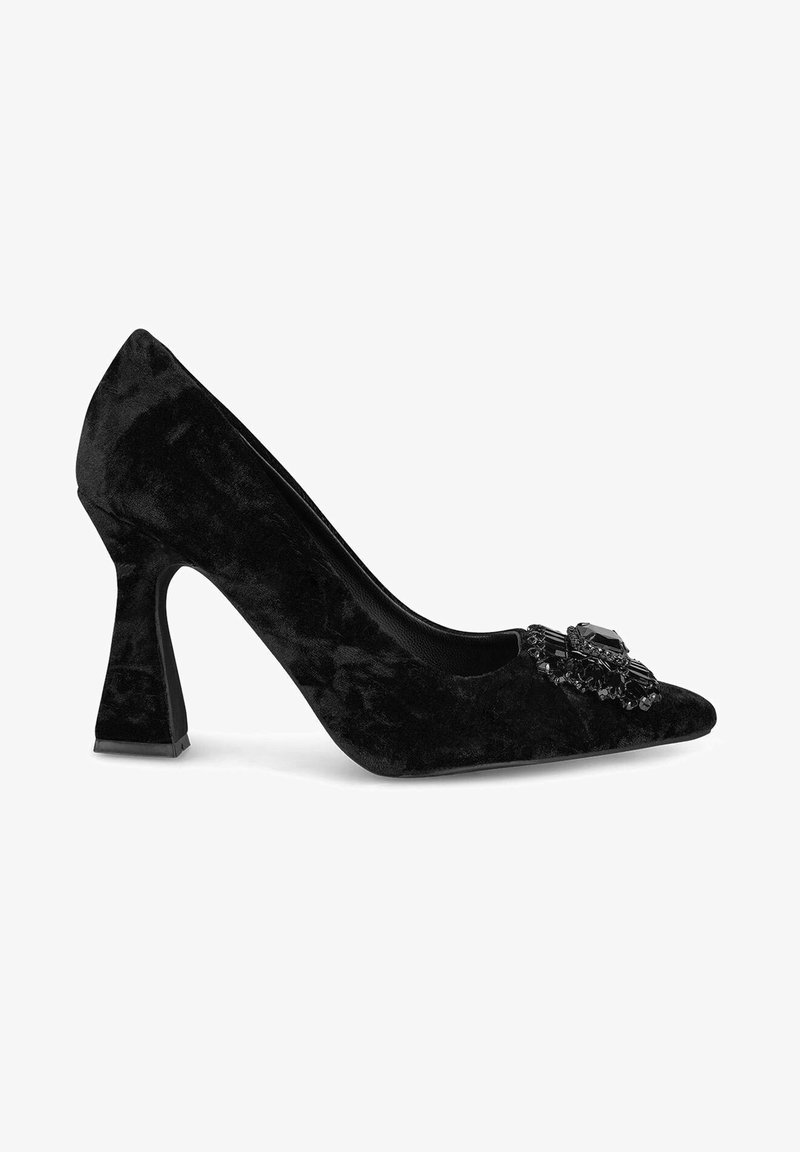 Chaussure à talon aiguille en velours noir avec un bout pointu, ornée d'un accent de bijou décoratif à l'avant et d'un talon carré sculptural.