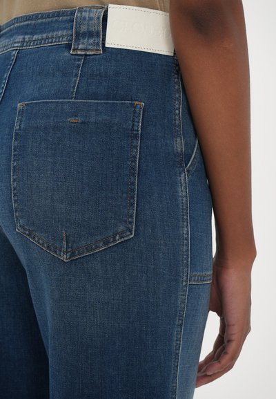 Denim jeans i blå farge, med fem lommer og diskrete søm detaljer. Inkluderer et hvitt lærlogo merke på livlinjen.