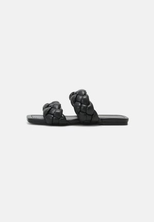 Czarna płaska sandałka typu slide z dwoma szerokimi, plecionymi skórzanymi paskami i kwadratowym noskiem na białym tle.