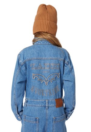 Veste en denim bleu avec un motif de broderie en forme de chauve-souris et des détails argentés dans le dos, assortie d'un bonnet beige en rib, marron.
