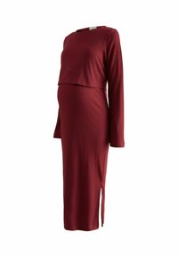 Ribbad burgundy gravidklänning med långa ärmar, sidoslits och ett lagerdesign, som framhäver en figurnära silhuett och mjuk textur.