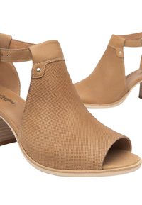 Scarpe aperte con punta quadrata, in pelle perforata, con cinturino alla caviglia e tacco in legno basso. Texture liscia con un design minimalista.