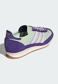 Fialová a mätovo zelená športová obuv so zamakom a syntetickými materiálmi, dizajnom troch pruhov a gumovou podrážkou s textúrovaným gripom.
