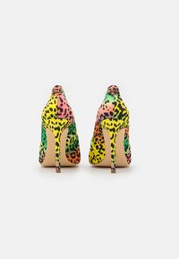 Chaussures à talons hauts arborant un imprimé léopard multicolore en rose, vert, jaune et noir, avec une silhouette élégante et un design à bout pointu.