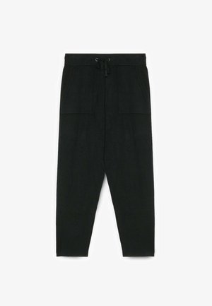 Pantalones negros de corte holgado con cordón en la cintura, que cuentan con dos bolsillos frontales y una textura suave, ajustándose en los tobillos.