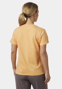 Camiseta de manga corta en algodón de color naranja claro, con un diseño simple que incluye un cuello redondo y una parte trasera lisa. Textura suave, sin adornos.