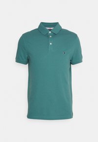Polo en coton teal avec un col classique, une patte de boutonnage à trois boutons et un petit logo brodé sur la poitrine. Manches courtes.