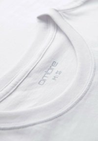 Nærbillede af hvid crew neck t-shirt, der viser ribbet krave og trykt størrelsesmærke "ombre M 48".