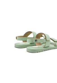Sandalias verde menta con dos correas ajustables, suela plana y fondo texturizado para mayor agarre. Presentan un pequeño logo en el lateral.