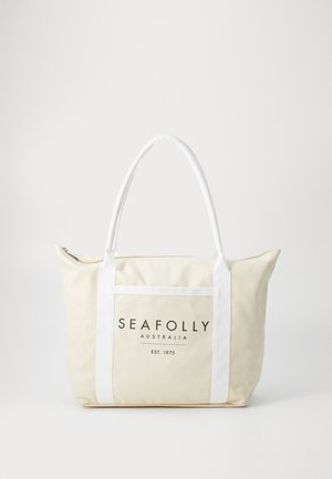Platnena torba u krem boji s bijelim ručkama. Ima prednji džep s logom "SEAFOLLY AUSTRALIJA" i zatvaranje na patentni zatvarač na vrhu.
