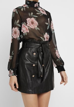 Sheer black blouse with pink floral print and high neckline, paired with a belted black leather skirt featuring gold buttons.