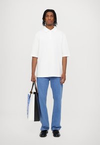 White short-sleeve polo shirt, denim blue straight-leg jeans, black shoes, and a tote bag with blue floral design. Simple and casual outfit.
