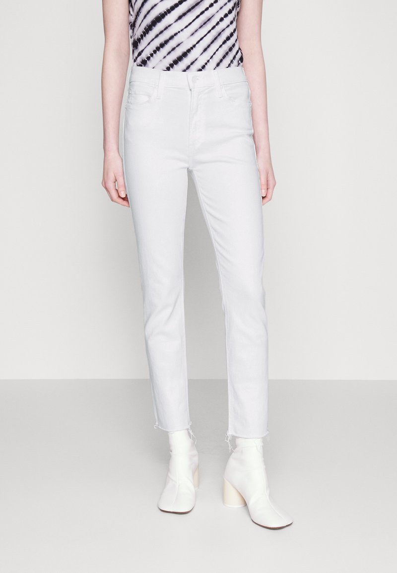 Hvit denimjeans med en tettsittende stil, med høy midje og råkant. Kombinert med en topp med svart og hvit tie-dye. Fottøyet er hvite ankelsko.