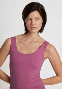 Pink tank top with a scoop neckline and thin straps. The fabric appears soft and stretchy, showcasing a smooth texture without patterns.