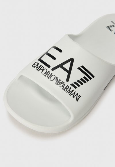 Бели сандали от гума с отворен нос. Имат черен печатан логотип "EA7 EMPORIO ARMANI" и диагонални райета. Гладка текстура.