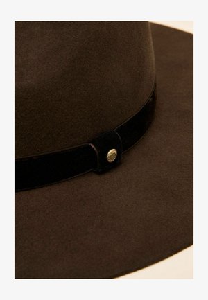 Brązowy kapelusz filcowy z szerokim rondem, aksamitną wstążką i metalicznym detalem na wstążce. Tekstura jest gładka z miękkim wykończeniem.