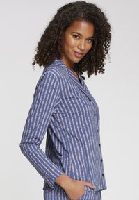 Plava dugoslojna pidžama s gumbima sprijeda. Tkanina ima vertikalni prugasti uzorak u nijansama plave i svijetlo ružičaste.