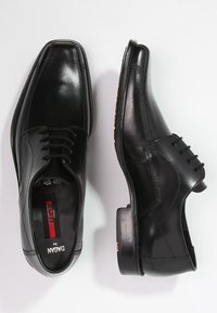 Chaussures habillées en cuir noir avec une finition brillante, design lacé, bout carré et détail de semelle contrastant. Présente une couture minimaliste.